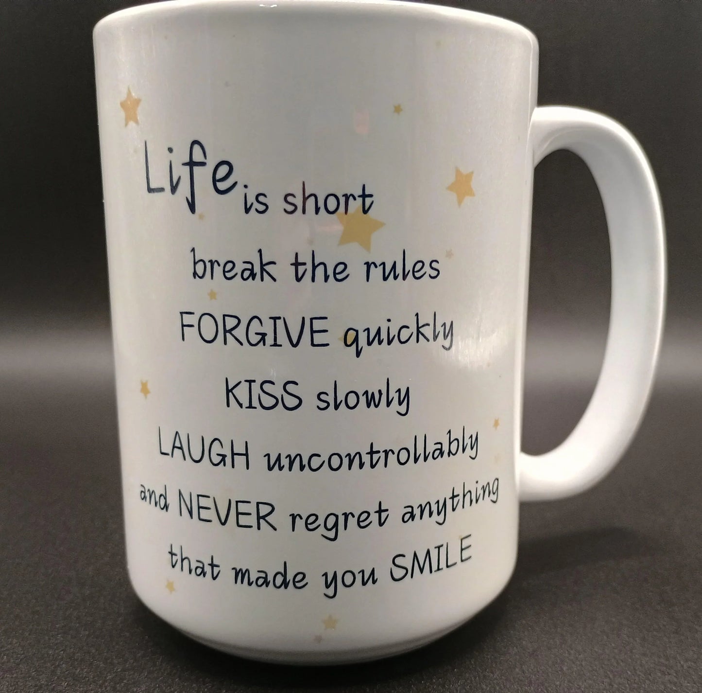 White ceramic mug with inspirational life quote and gold stars on black background