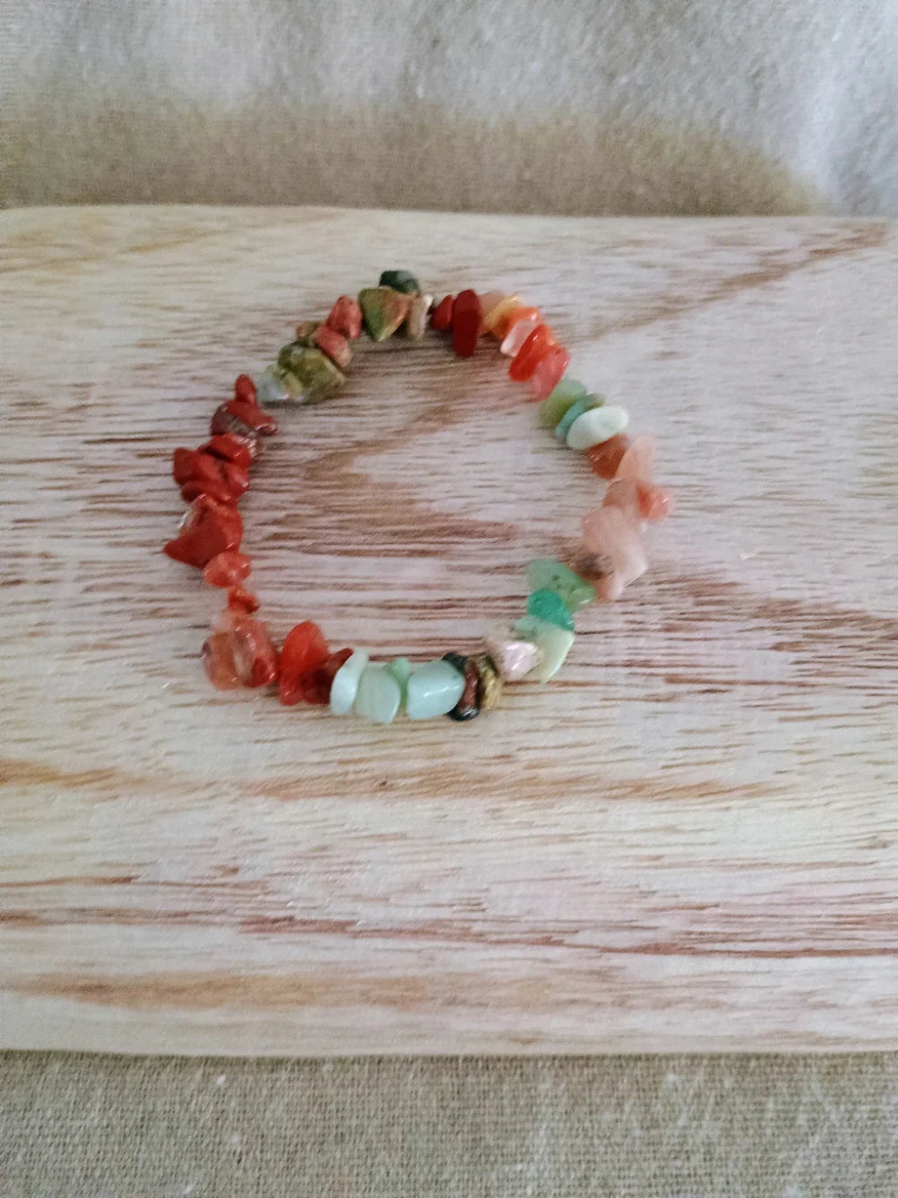 Colorful beaded bracelet with irregular gemstone chips on wooden surface