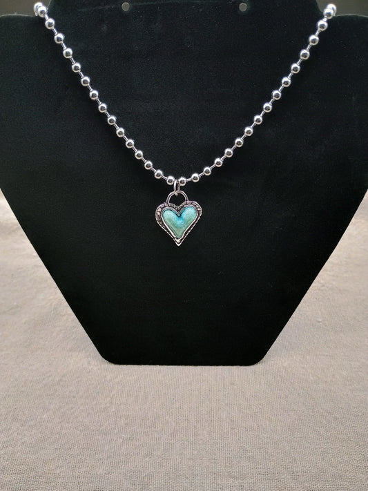 Silver ball chain necklace with turquoise heart pendant on black display stand