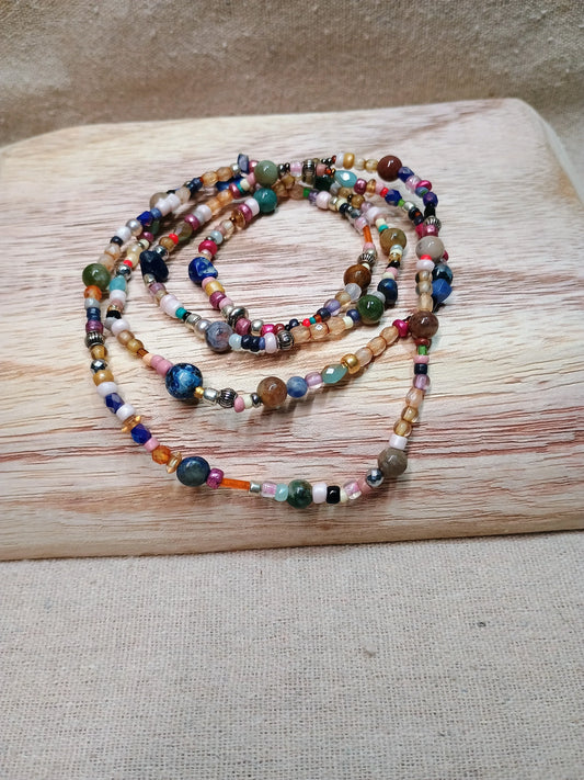Colorful beaded necklace with various round and faceted beads on wooden board background