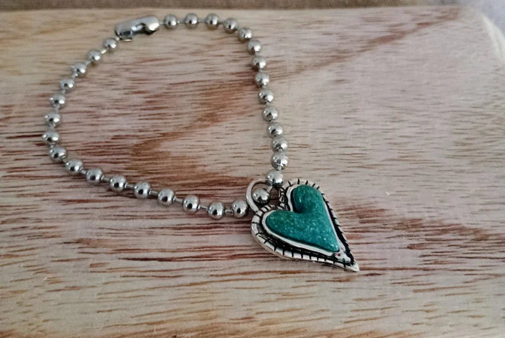 Silver ball chain keychain with a turquoise heart-shaped charm on wooden surface