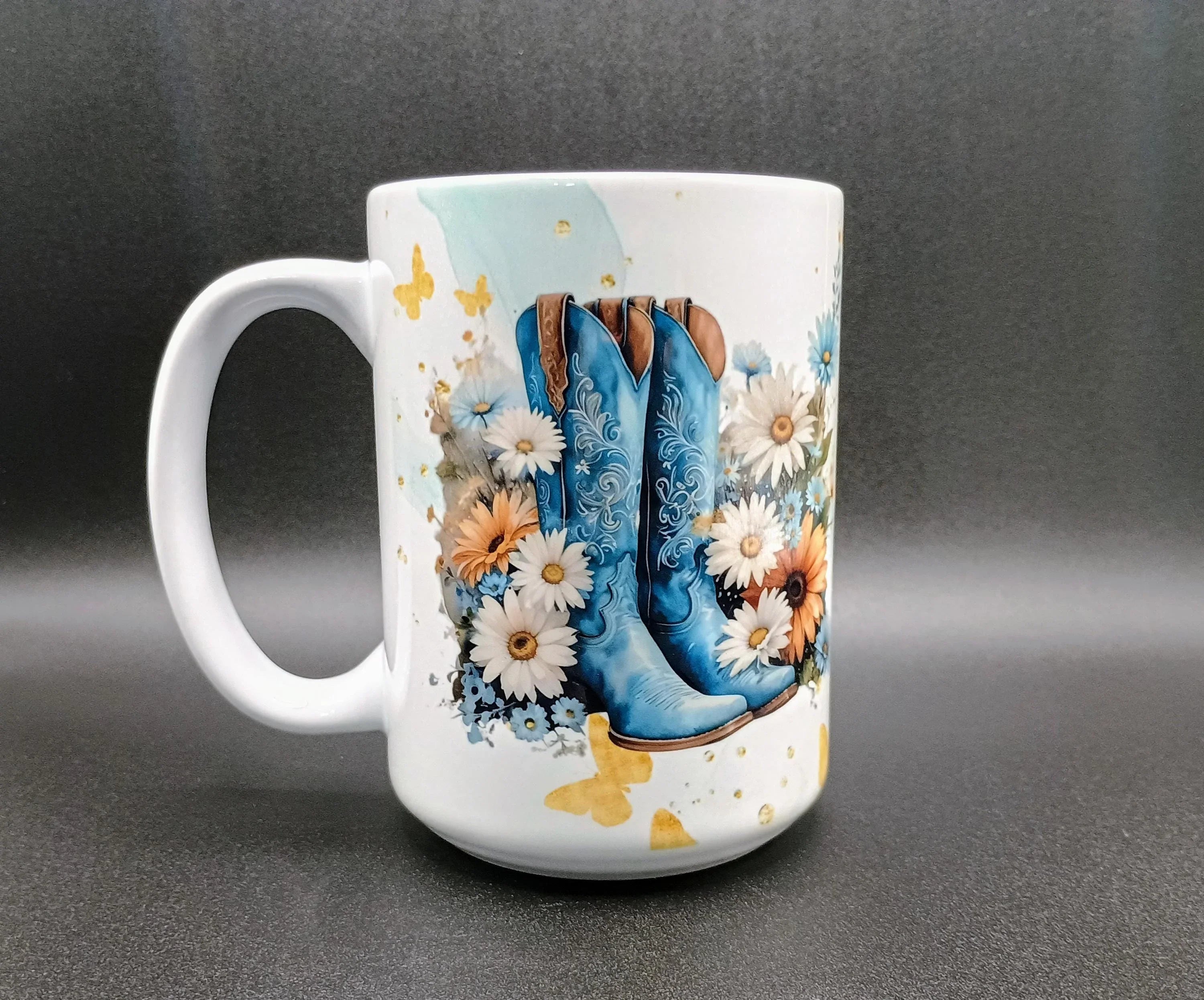 White ceramic mug with blue cowboy boots, white and orange daisies, and yellow butterfly design