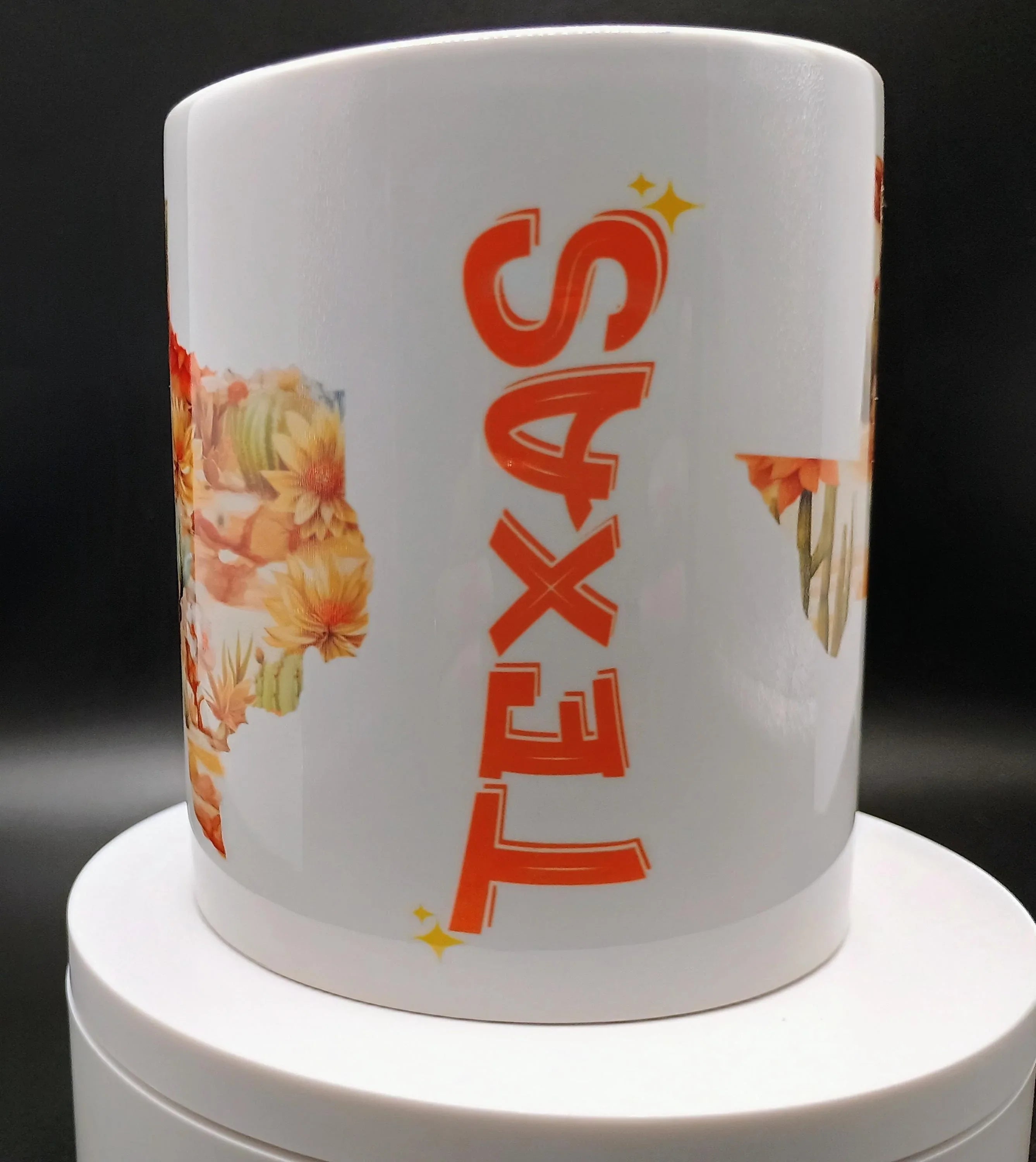White ceramic Texas mug with orange floral cactus design on white rotating stand