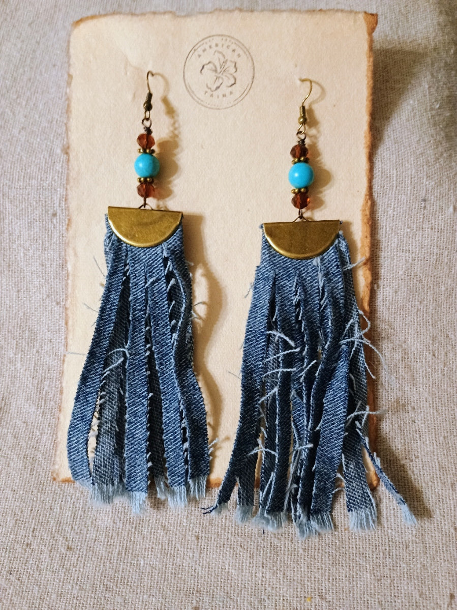 Denim fringe earrings with turquoise beads on a textured surface