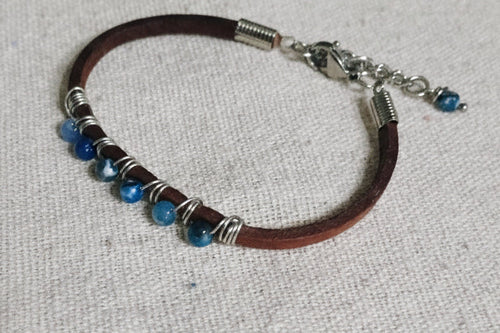 Bracelet with beads and leather strap on a textured surface