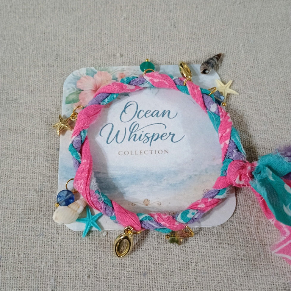 Colorful braided bracelet with charms on a 'Ocean Whisper Collection' card.