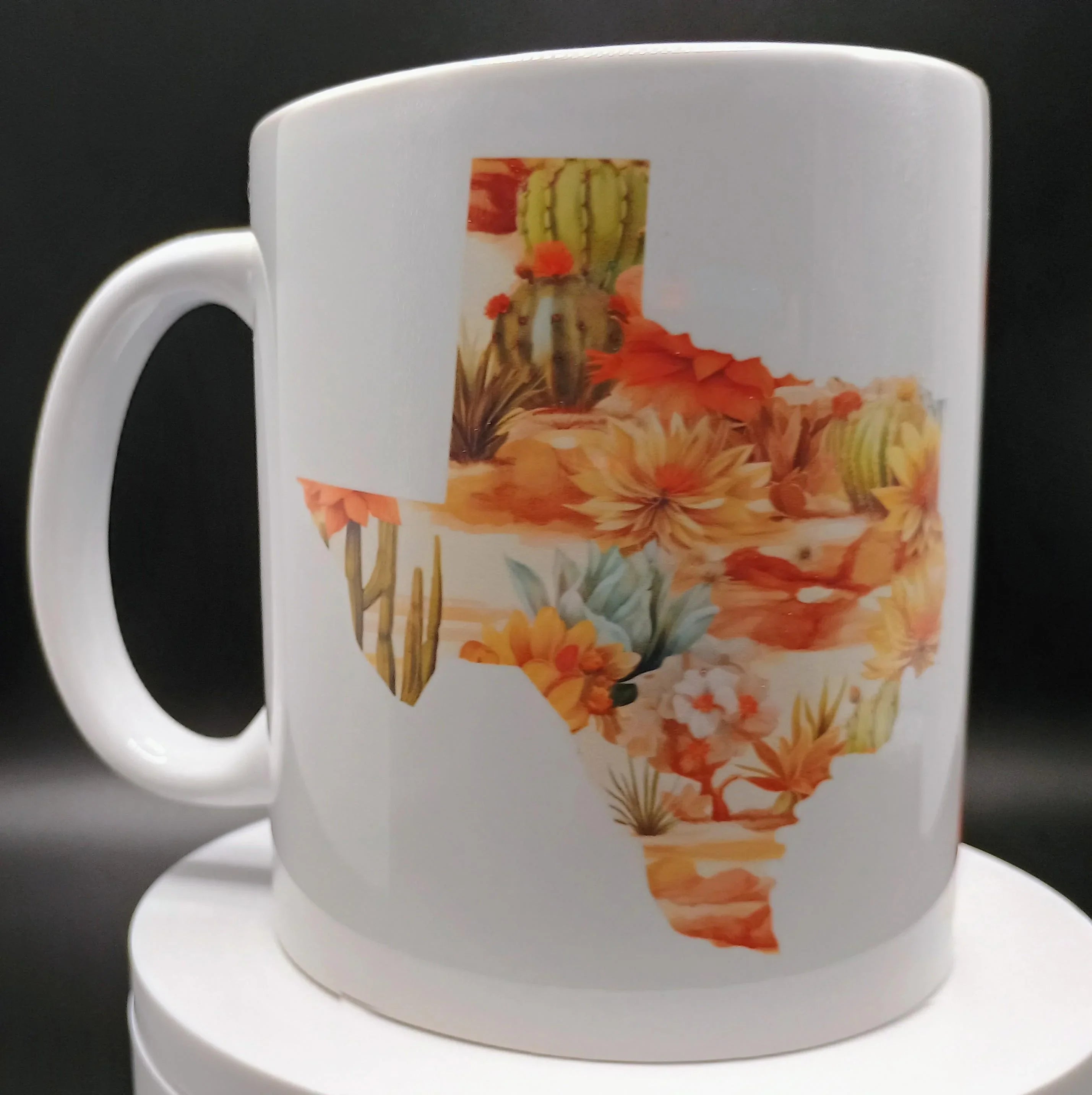 White ceramic mug with Texas state shape filled with colorful desert cactus and flower design