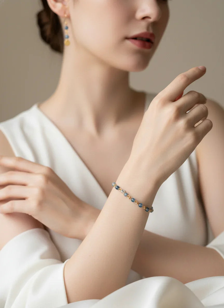 Close-up of woman wearing blue agate bead bracelet and matching earrings in white dress