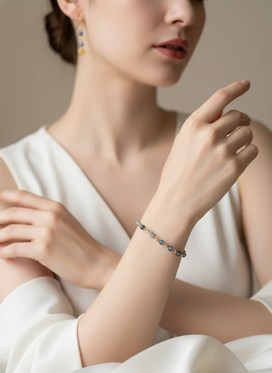 Close-up of woman wearing blue agate bead bracelet and matching earrings in white dress