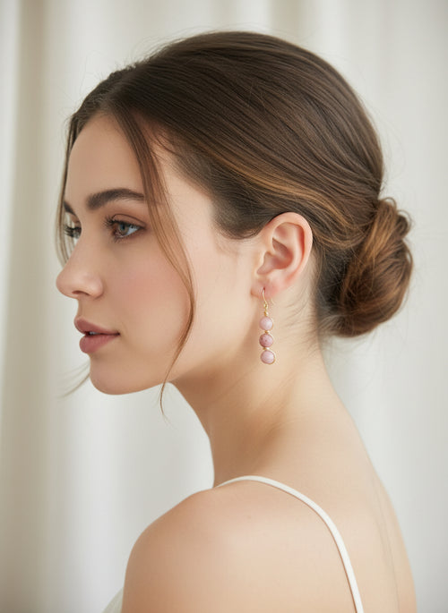Profile of woman with blush pink gemstone drop earrings and brown hair in a low bun