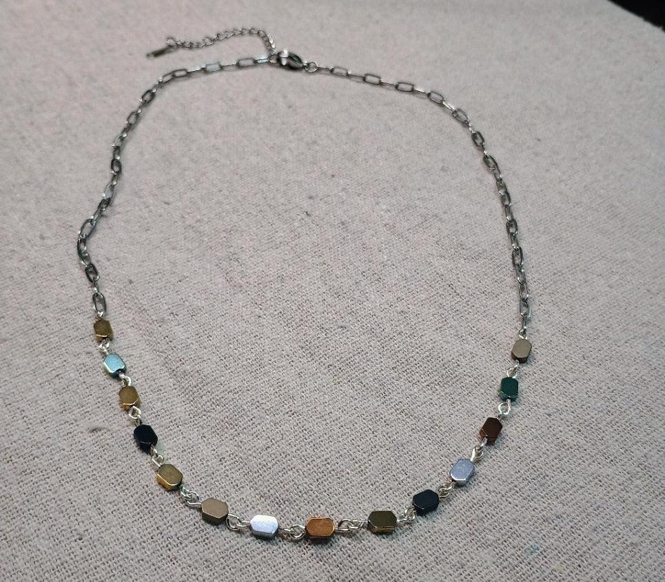 Silver chain hematite necklace with multicolored hexagonal beads on beige fabric background