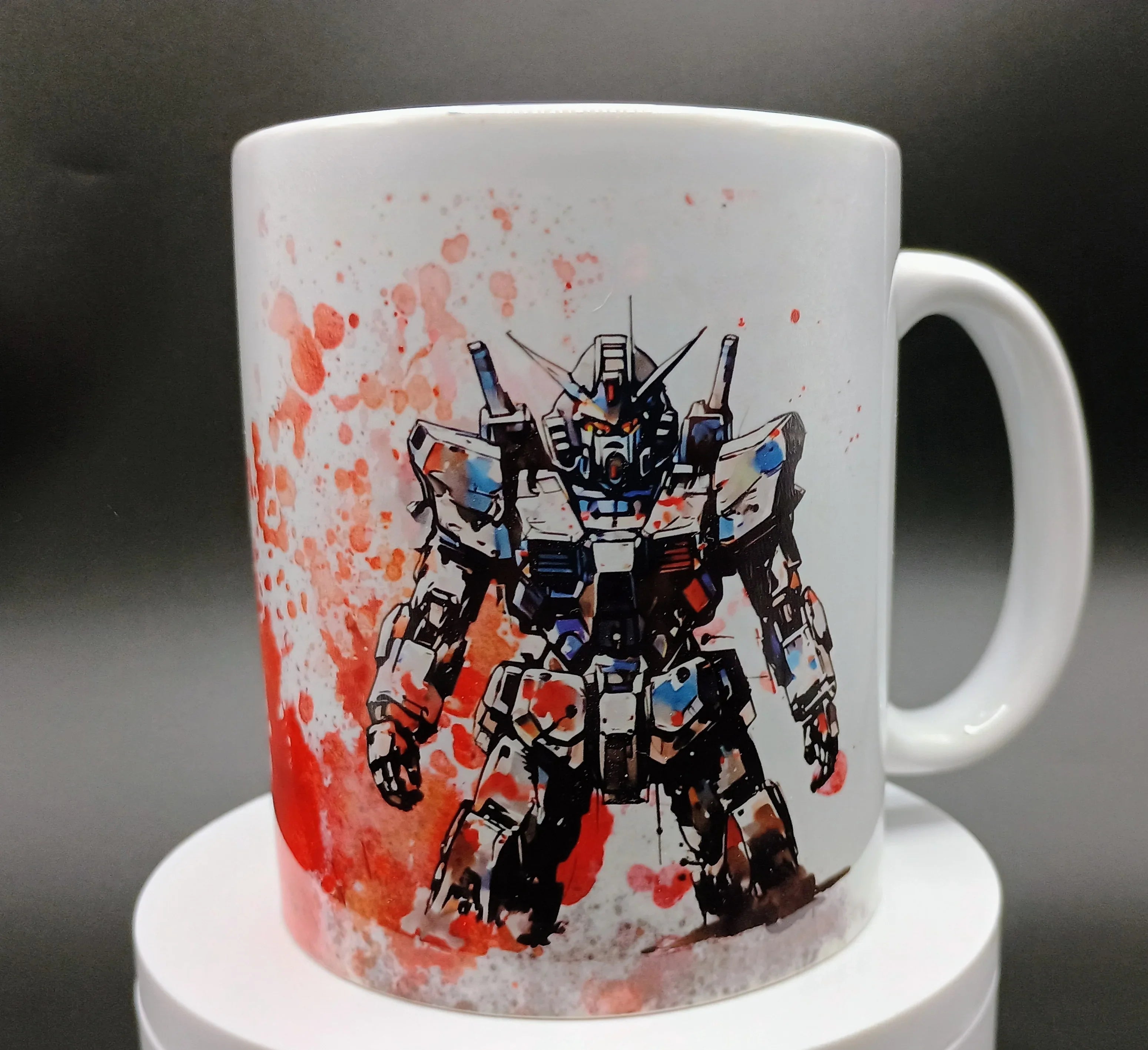 White mug featuring a colorful Gundam robot illustration with red splatter art background
