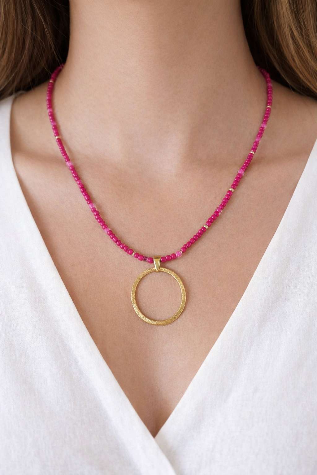 Necklace with pink beads and a gold pendant on a white background