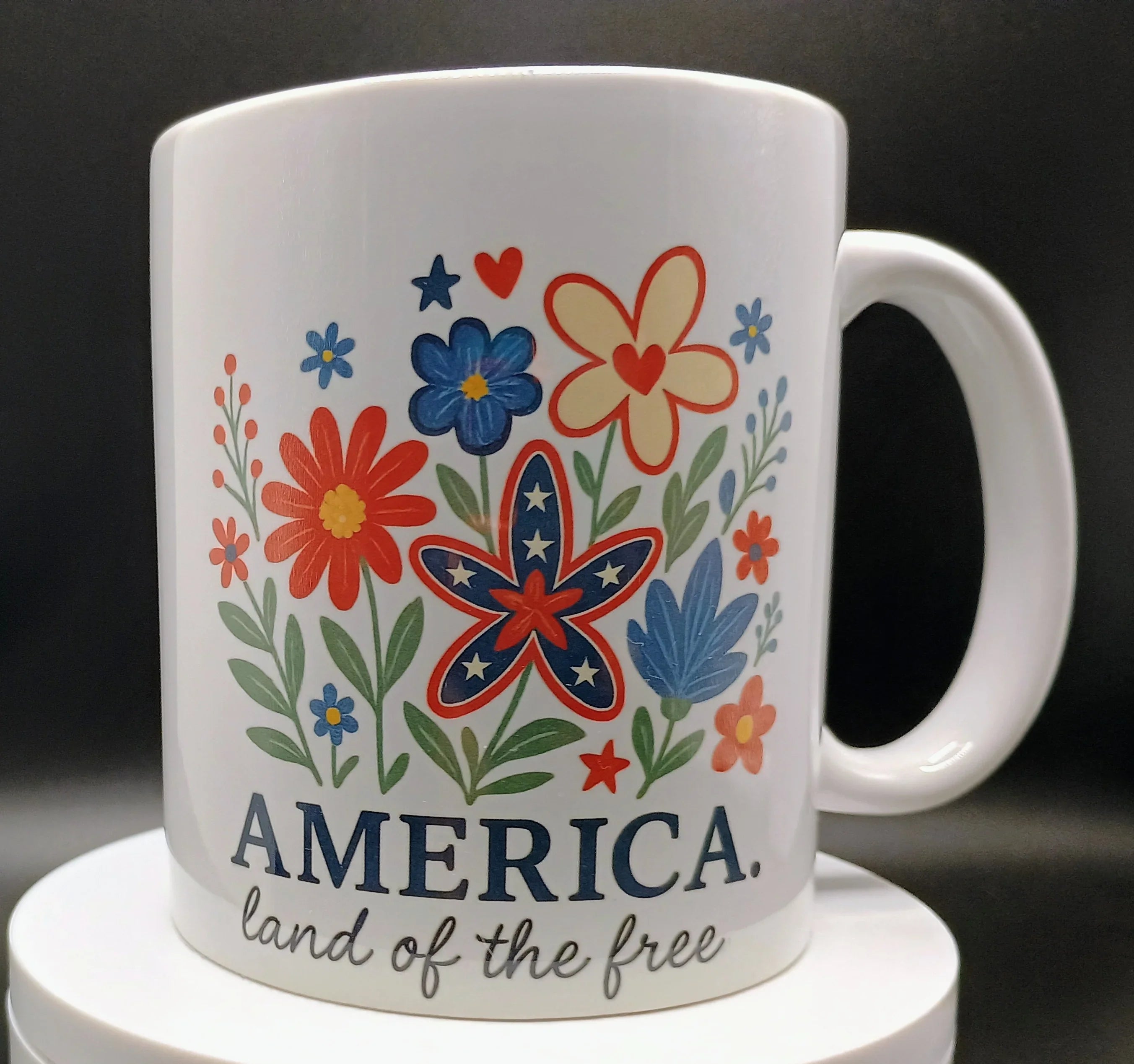White ceramic mug with colorful patriotic flowers and text America land of the free
